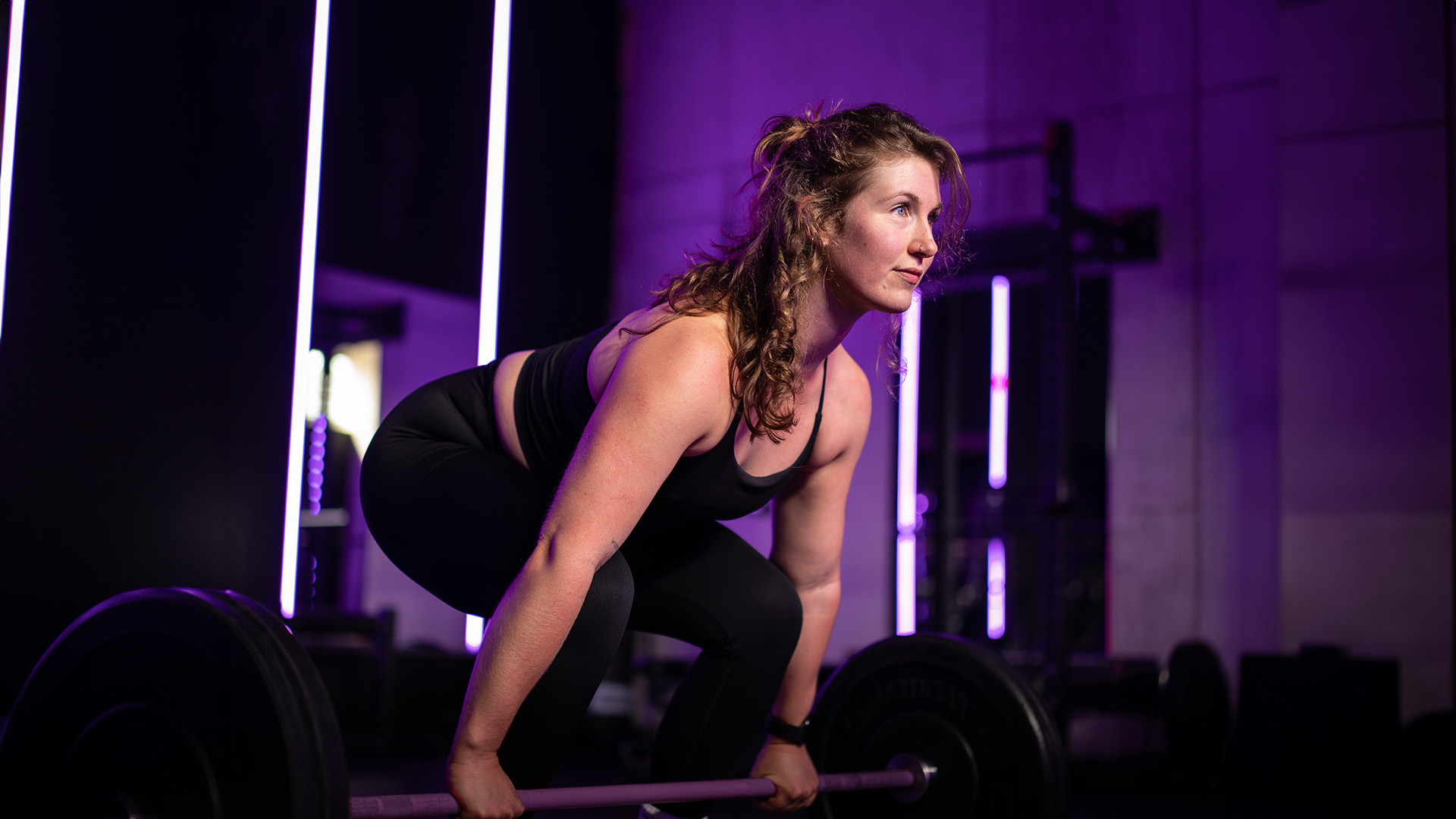 Een dame die zich klaarmaakt een zwaar gewicht te tillen in de sportschool